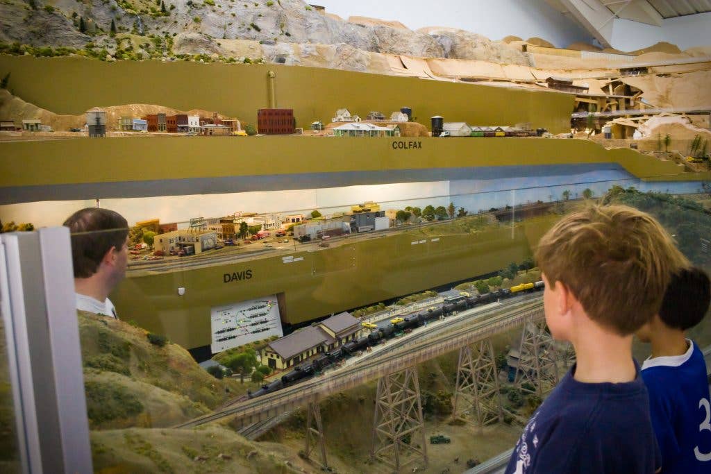Father and sons working on a model train layout